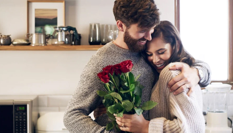 a pair of couple hugging each other with a bouquet of rose